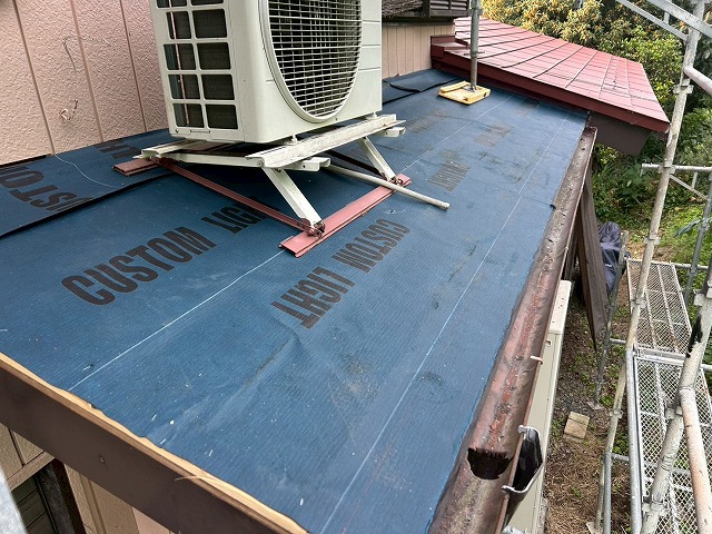 都留市で下屋根に粘着層付の改質アスファルトルーフィングを設置する様子