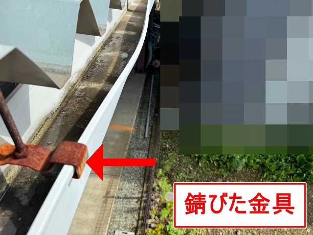富士吉田市で折板屋根に設置された雨樋が歪んでおり、吊り金具が錆びている様子